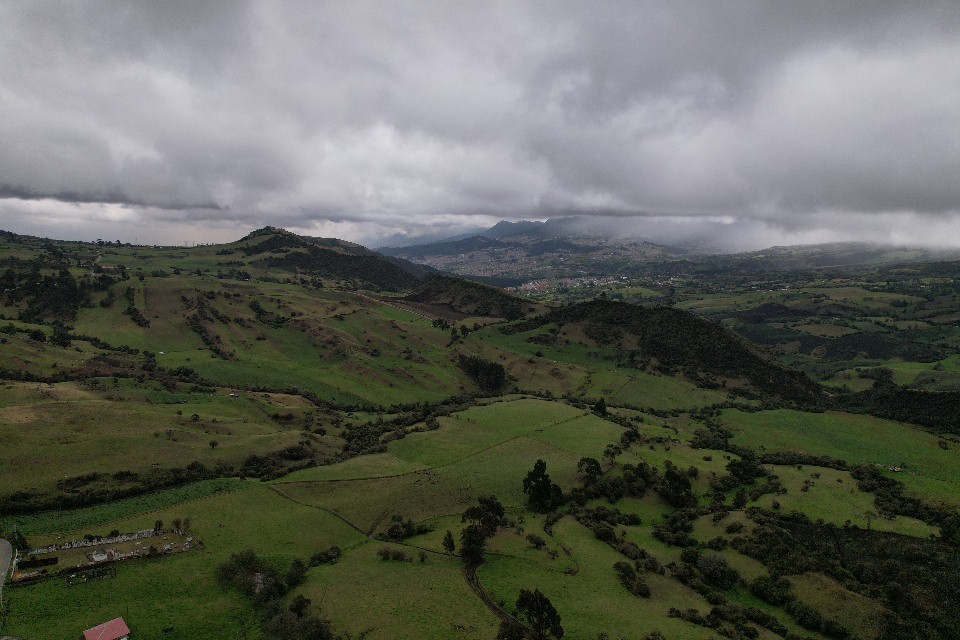 Paisaje de montañas verdes con cielo gris oscuro sin construcciones alrededor.