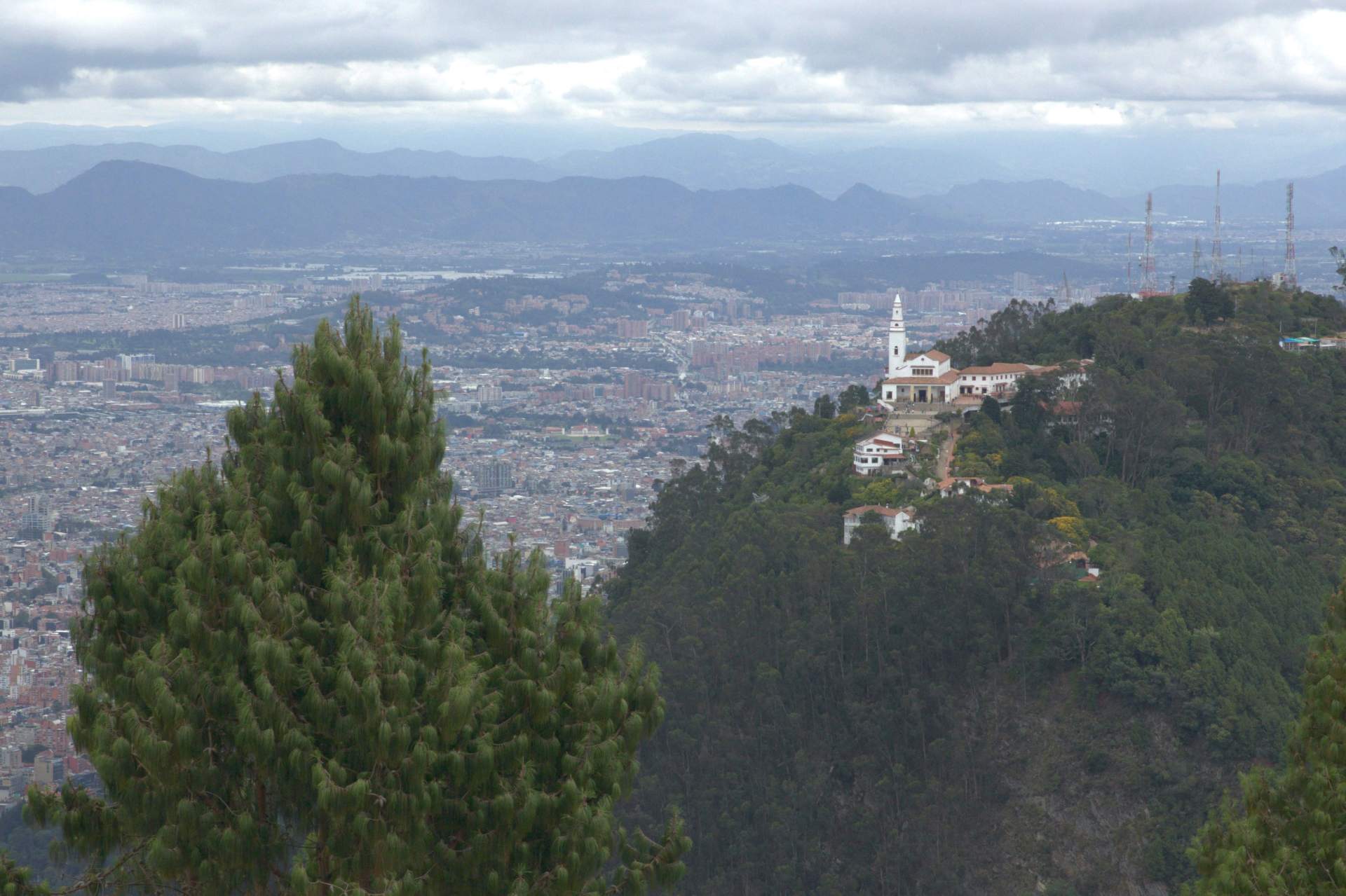  La ciudad de Bogotá desde el cerro de Guadalupe, se ve la iglesia de Monserrate en el cerro de al lado rodeados por grande árboles.
