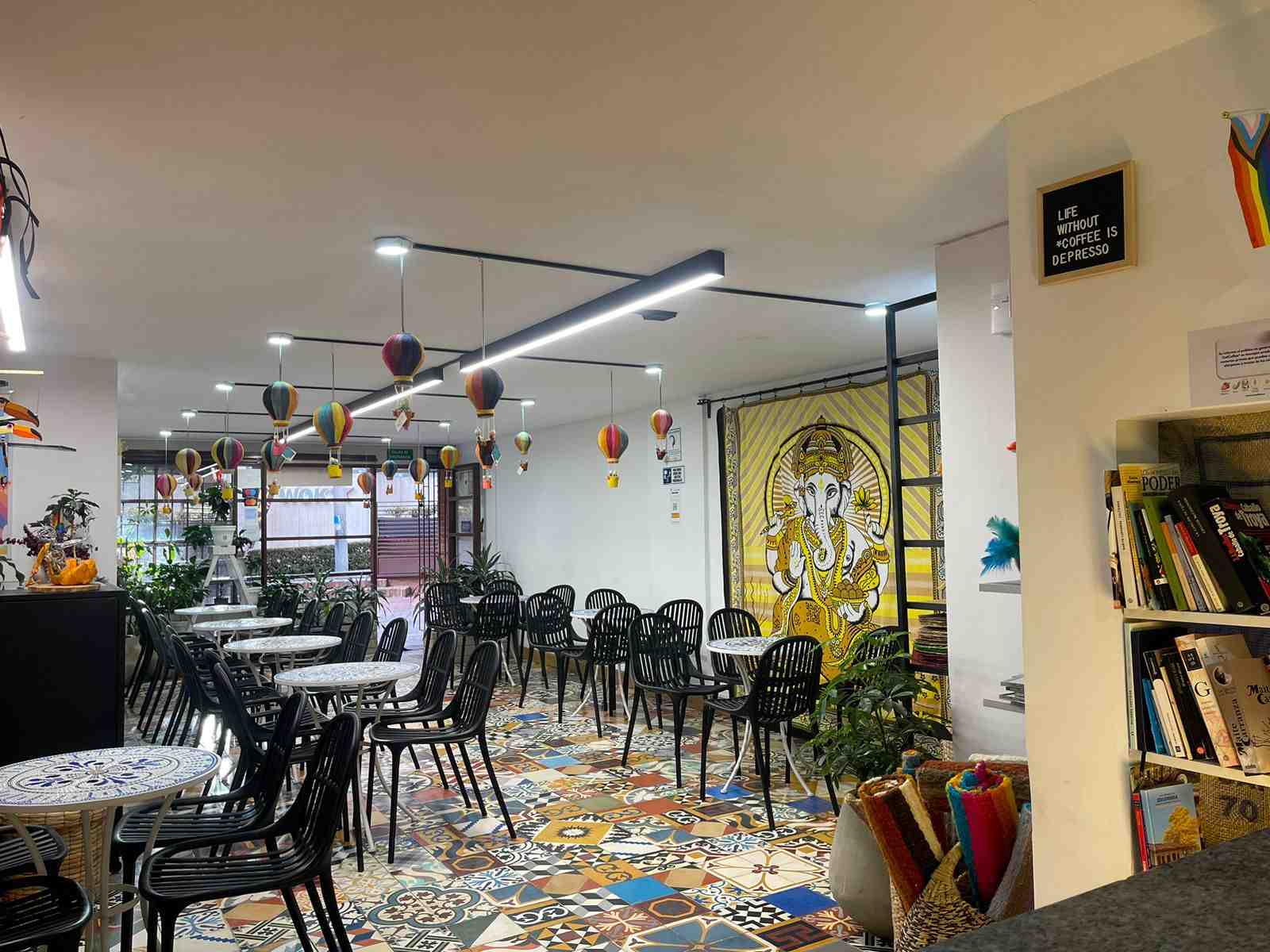 Interior de restaurante de estilo árabe con varias mesas  redondas y sillas alrededor de ellas. Del techo cuelgan unos adornos en forma de globos con canastas.