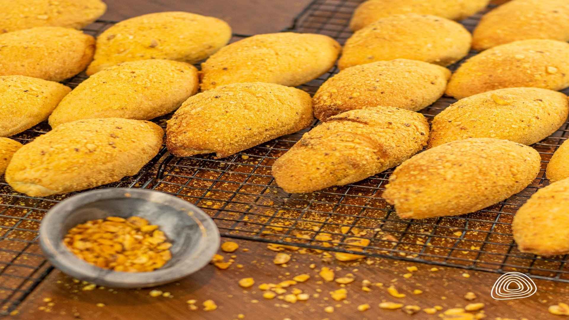 Muchos panes pequeños y ovalados con una cobertura crujiente, enfriándose en una rejilla.