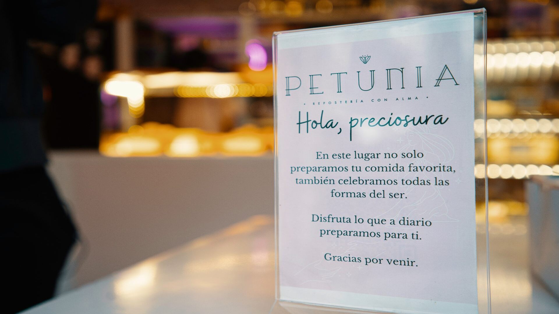 Un letrero enmarcado de "Petunia Repostería con Alma", con un mensaje de bienvenida cálido a los clientes.