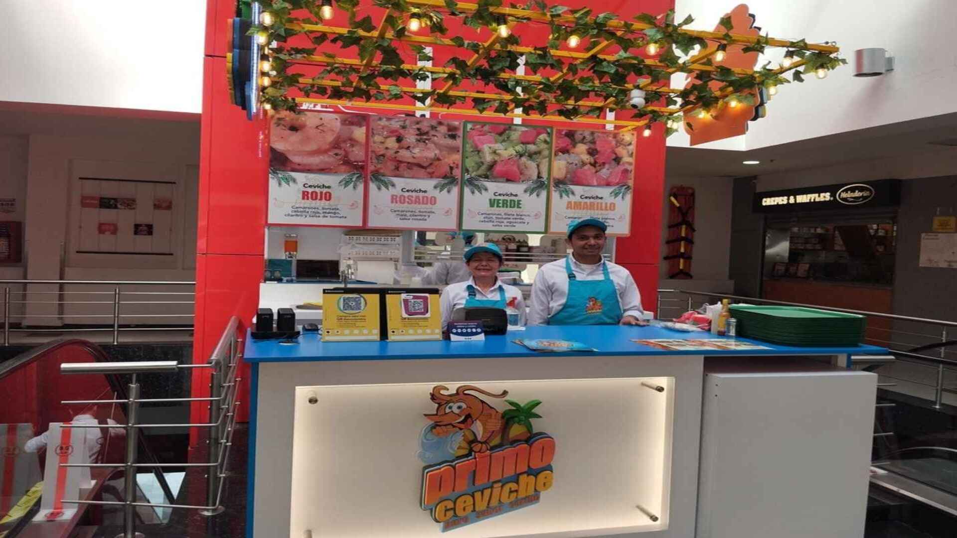  Un puesto de ceviches con dos empleados sonrientes, ofreciendo variedades rojo, rosado, verde y amarillo.