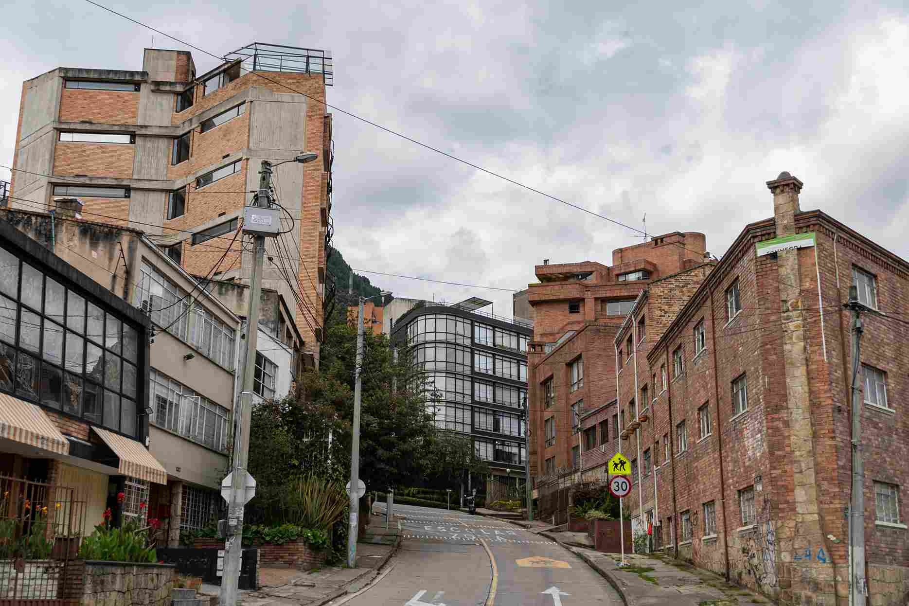 Calle residencial vista desde abajo rodeada de edificos en ladrillo al estilo de los años 70 y 80.