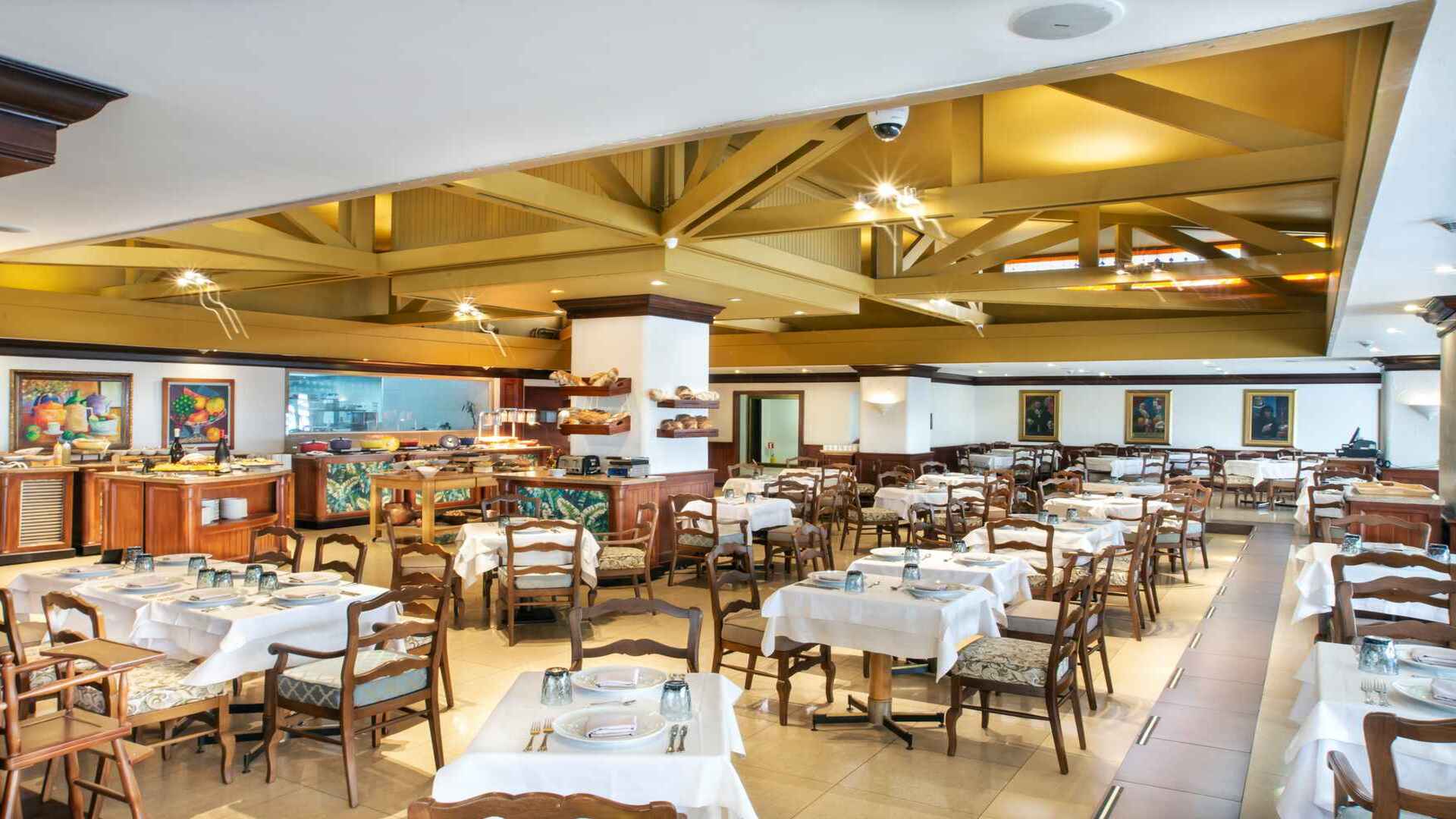 Restaurante de hotel con mesas vestidas y un buffet. Amplio comedor con un diseño clásico y ambiente acogedor.