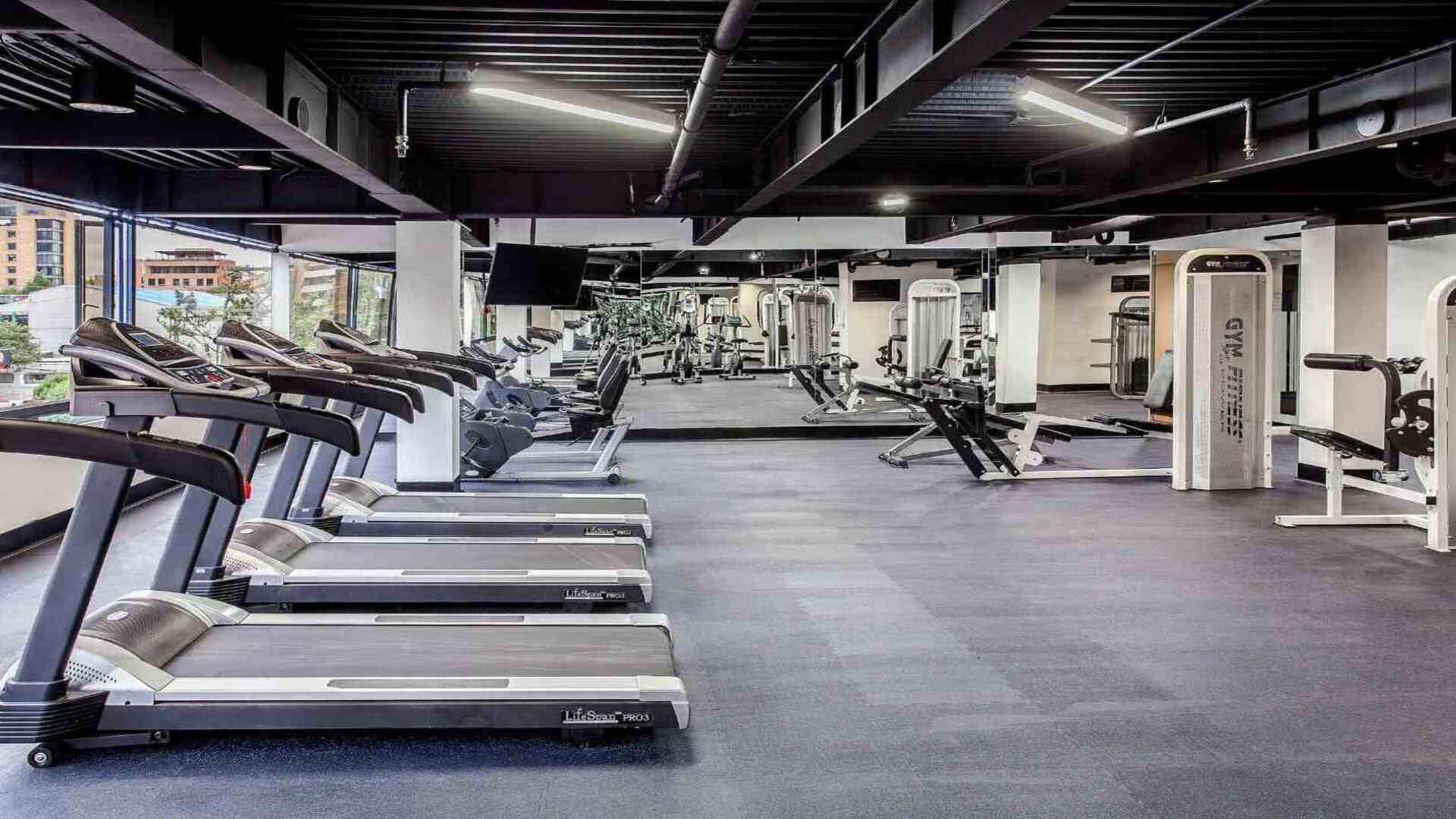 Un gimnasio de hotel amplio y bien equipado, con cintas de correr, máquinas de pesas y otros equipos de fitness, ideal para mantenerse activo.
