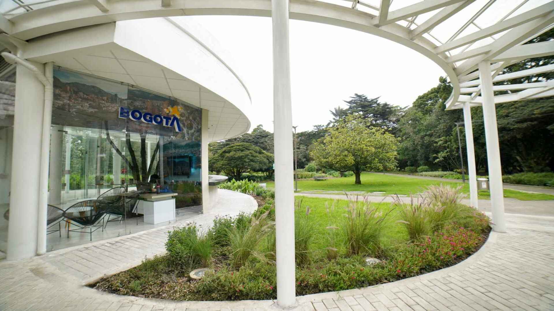 Un elegante edificio curvo que alberga un punto de información turística, rodeado de vegetación exuberante.