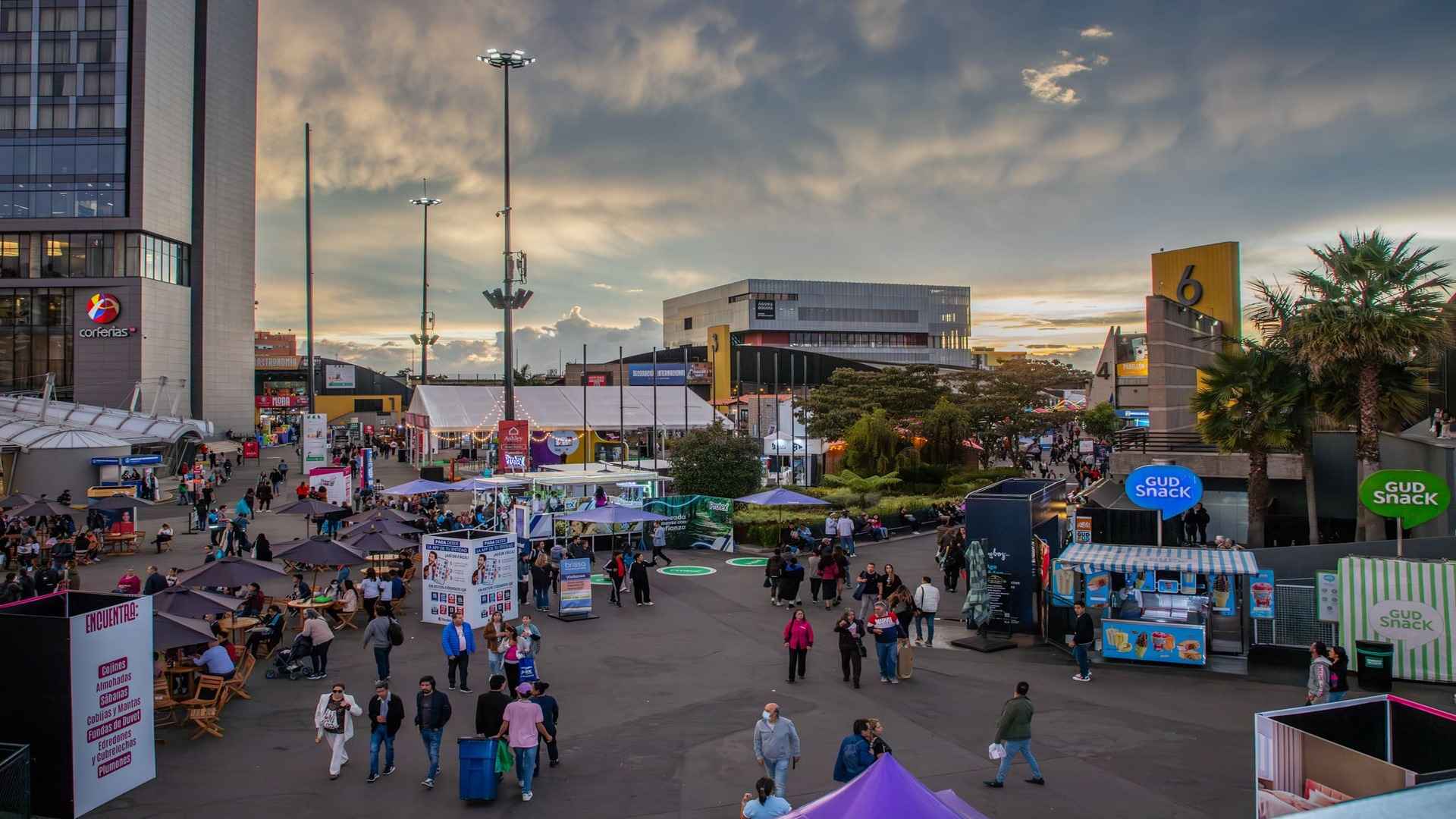 Pasillos concurridos de una feria empresarial con diversos stands de exhibición profesional y personas interactuando.